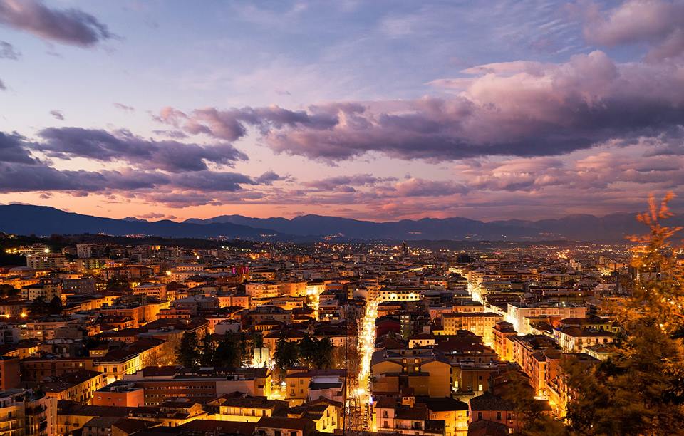 Cosenza al tramonto, con le luci della città accese e le montagne della Sila sullo sfondo